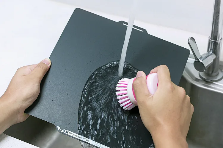 プレートを洗浄する公式写真。温水と食器用洗剤で油脂や汚れを落とす